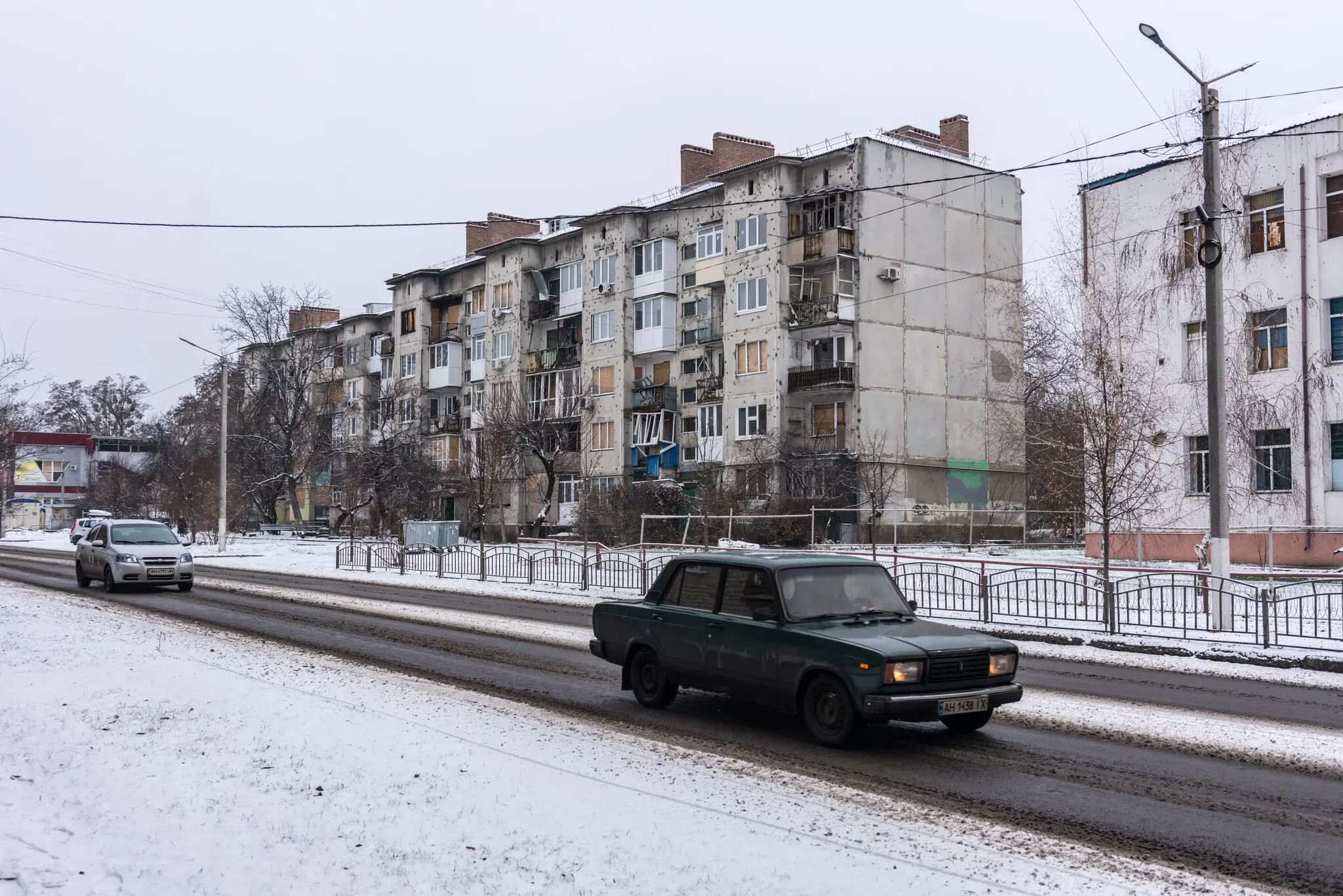 Автомобілі проїжджають повз пошкоджений житловий будинок у Слов'янську, Україна, 24 січня.